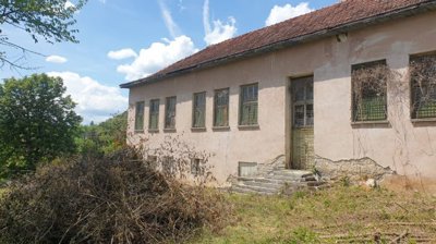 Old school side wall showing barred windows and metal gate door with stone steps