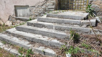 Stone steps leading up to barred metal gate door on old school building exterior