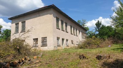 Side perspective of the old school building with barred windows and trimmed vegetation in the yard