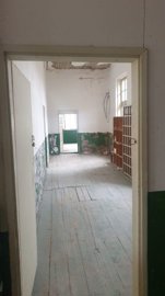 Room inside the building showing peeling paint on walls and wooden floorboards
