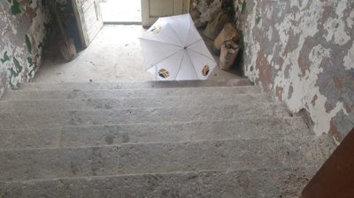 Stone staircase inside the old school building with an umbrella on the steps and worn walls