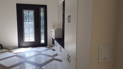 Entryway featuring built-in storage bench with handles and decorative glass door