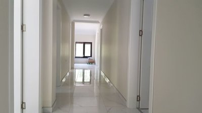 Bright indoor corridor with white walls, multiple doors, and window at end