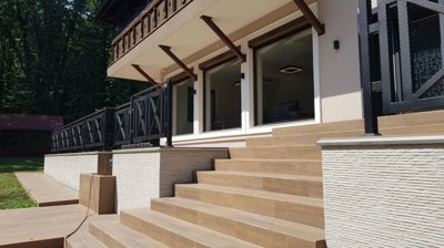 Close-up of stairs leading to terrace with black metal railing and textured wall