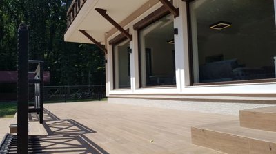Terrace area with large windows overlooking forest and tiled floor