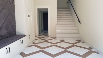 Indoor staircase with white walls, black handrail, and patterned tiled floor