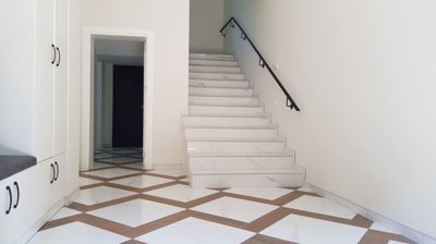 View of indoor staircase and hallway with white walls and patterned tiles