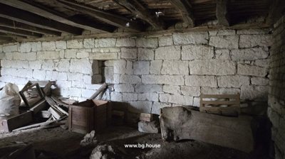 Stone basement wall with exposed wooden beams overhead and wooden crates alongside scattered debris on the floor.