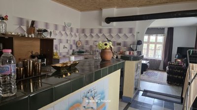 Kitchen counter with tiled surface and various kitchen items including a vase with flowers