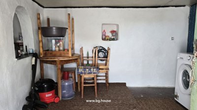 Room interior featuring white walls, stacked wooden chairs, table, and washing machine