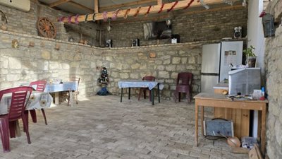 Spacious indoor dining area featuring stone walls, plastic chairs, tables, and decorative items.