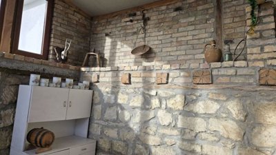 Stone wall interior with window, wooden cabinet, and decorative objects on shelves.