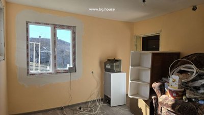 Room with peach-colored walls, a window, and various furniture and household items
