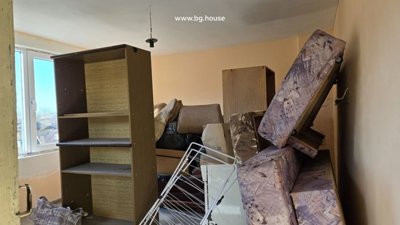 Interior room containing stacked furniture, mattresses, and various household items