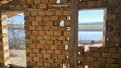 View of lake and countryside seen through a large window opening in the unfinished villa room.