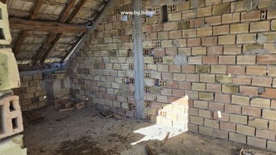Interior view of an unfinished attic space showing exposed brick walls and wooden roof structure.