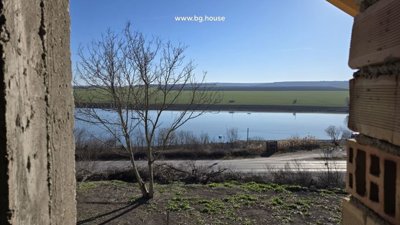 Scenic view of a lake and surrounding fields seen through an unfinished window opening with a tree in the foreground.