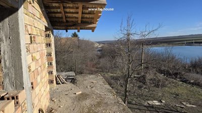 Outdoor balcony area showing unfinished brick walls and roof overhang with views of trees and sky.