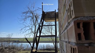 Metal staircase leading to upper level attached to the villa's exterior wall with lake and fields in the background.