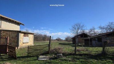 View of fenced yard featuring a brick outbuilding and open rural landscape with trees