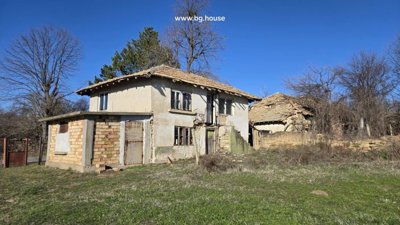 Two-storey rural house with plastered walls and adjacent old stone building in grassy yard