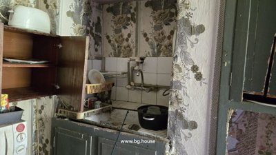 Kitchen corner featuring a sink with tiled backsplash, open cupboards, and various kitchen items