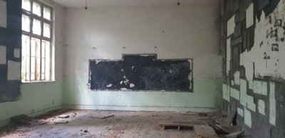 Old school room showing blackboard area and walls with patchwork repairs