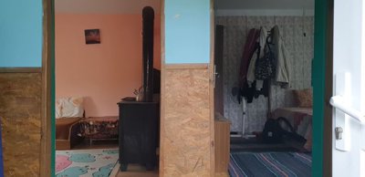 View of two interior rooms with peach walls, a wood stove, and furniture including a sofa and table