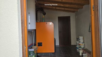 Utility room featuring orange heating unit, white water heater, and closed wooden door