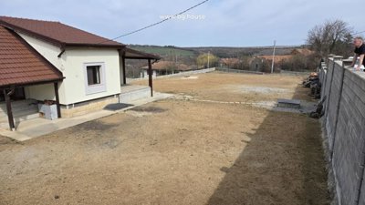 Yard space beside the house showing concrete surface, boundary wall, and some stored items