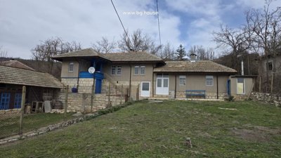 Front view of a traditional Bulgarian house with stone foundation and tiled roof in Kostandenets village