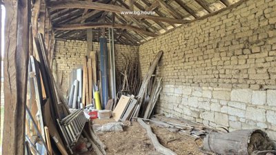 Inside view of a wooden shed showing exposed beams and various stored wood and building materials