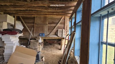 View inside wooden shed showing blue window frames and stacked construction materials