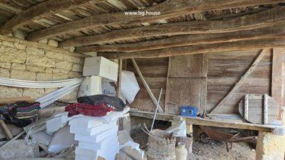 Storage area inside wooden shed with stacked boxes, blankets, and other items