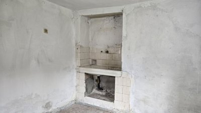 Indoor corner featuring a built-in sink with a tiled backsplash in a white plastered room