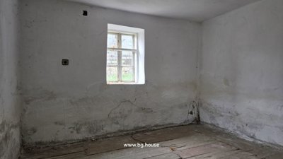 Empty indoor room with white plastered walls and a window providing natural light