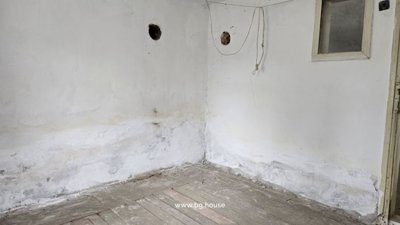 Indoor room showing white plastered walls with two circular holes and hanging wires