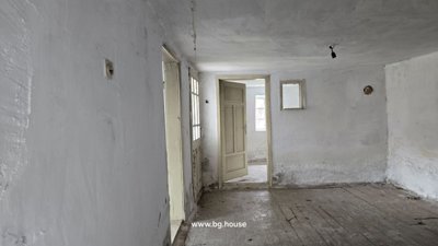 Interior room with white plastered walls, wooden floorboards, and doorways leading to other rooms