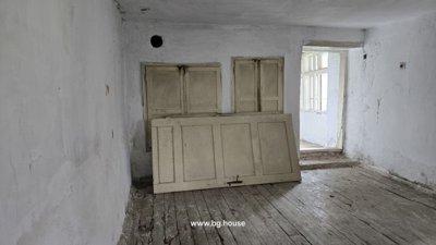 Interior room with white walls, wooden floor, and a detached door panel resting against the wall