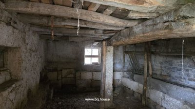 Inside a stone barn showing exposed wooden beams and a small window providing natural light.