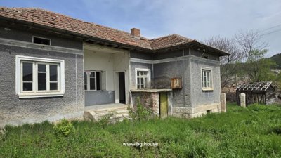 Side perspective of the Bulgarian house with visible windows, tiled roof, and garden space