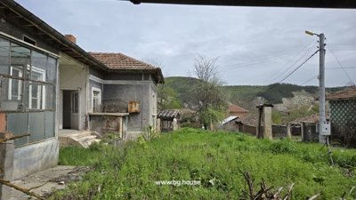 Bulgarian rural house exterior with garden and scenic hills in the background