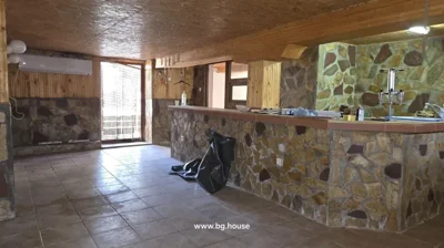 Room featuring stone walls, bar counter, and tiled floor with natural light