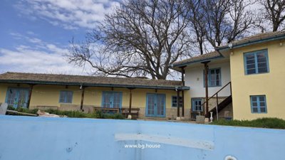 Yellow rural house with blue windows and empty swimming pool surrounded by stone patio