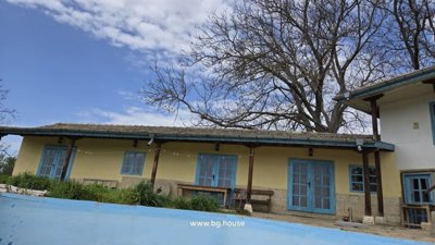 Yellow rural house with blue windows and empty swimming pool with stone patio