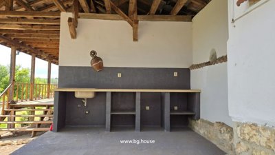 Outdoor kitchen space on the veranda with stone counters and wooden roof overhead