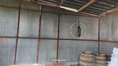 Inside view of a metal shed showing corrugated walls and storage barrels