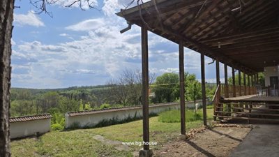 View from the veranda overlooking the garden area, stone wall, and distant countryside
