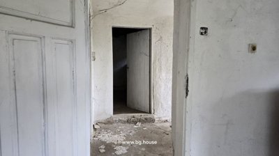 Interior corridor showing whitewashed walls and open doors leading to other rooms.