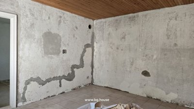 Another angle of the bathroom showing tiled walls and floor, a toilet bowl, and a wall-mounted basin.